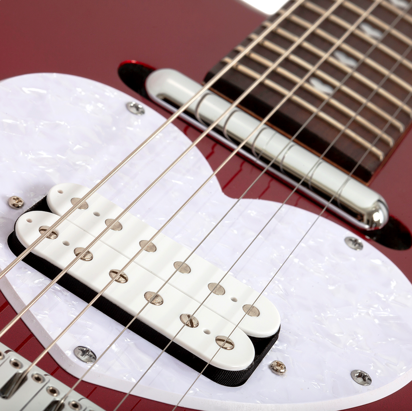 Close-up of a short scale red electric guitar bridge and strings with a white pearlescent pick guard