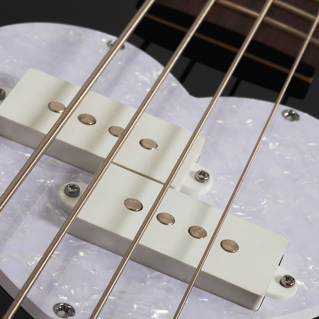 Close-up of a back electric bass guitar bridge and strings with a white pearlescent pick guard