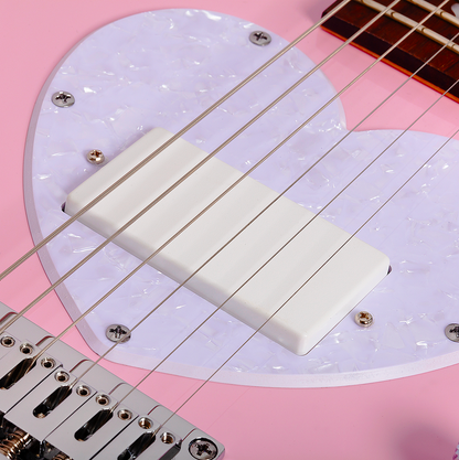 Close-up of a short scale pink electric guitar bridge and strings with a white pearlescent pick guard