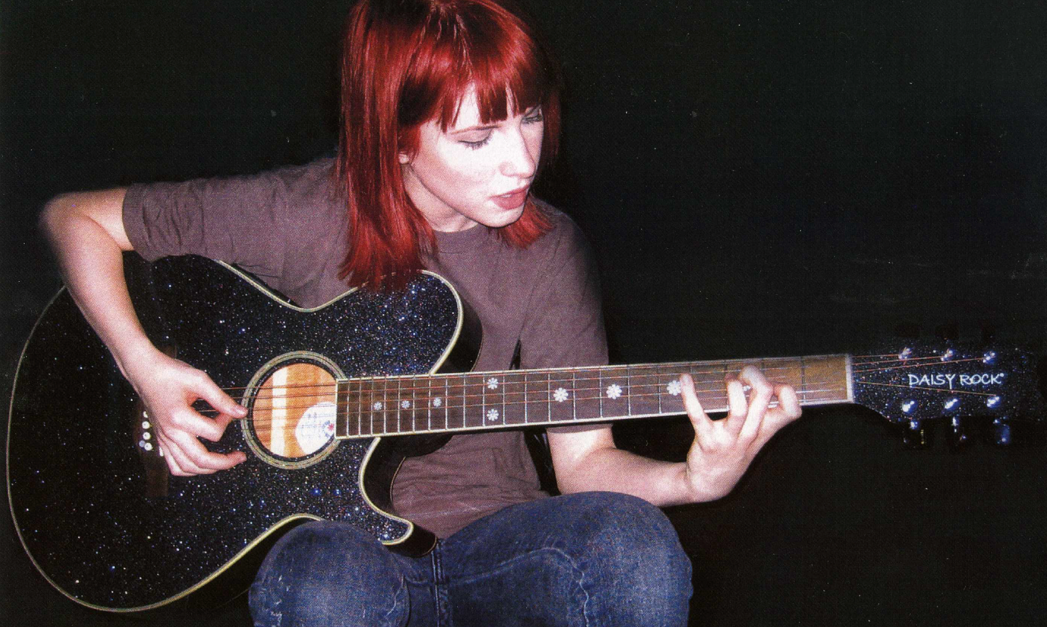 Photo of Haley Williams playing a black, sparkly Daisy Rock acoustic guitar
